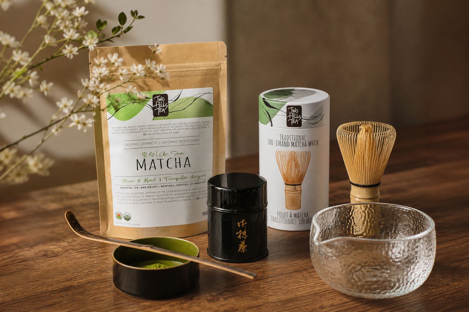 Two Hills Tea matcha gift set with whisk, matcha pouch, tea tin, and glass bowl in warm aesthetic setting